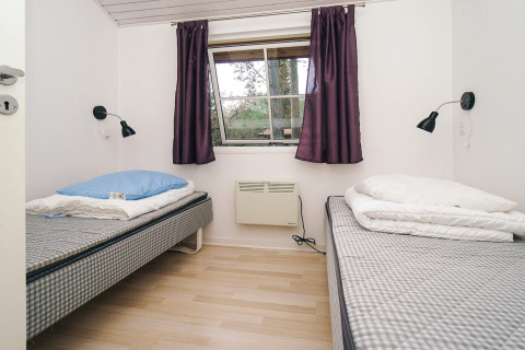 Camera da letto con due letti singoli, tende viola e lampade a parete in una casa vacanza a Store Fuglede.