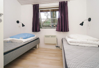 Schlafzimmer mit zwei Einzelbetten, lila Vorhängen und Wandlampen in einem Chalet in Store Fuglede.