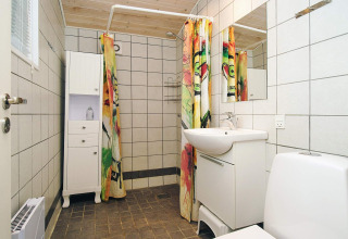 Baño moderno con azulejos blancos, cortina de ducha colorida y techo de madera en chalet danés.