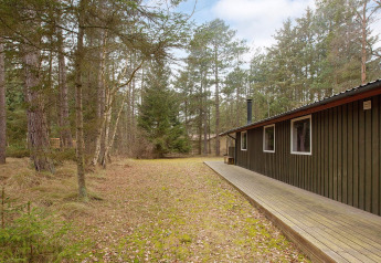 Chalet para seis en Store Fuglede, Dinamarca, con terraza de madera rodeado de un tranquilo bosque natural.