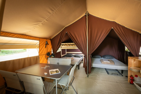 Interieur van een safari bungalowtent Classic met bedden en eettafel bij Huttopia Chardons Bleus - Ile de Ré.