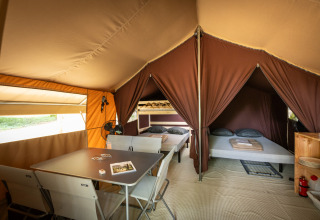Interieur van een safari bungalowtent Classic met bedden en eettafel bij Huttopia Chardons Bleus - Ile de Ré.