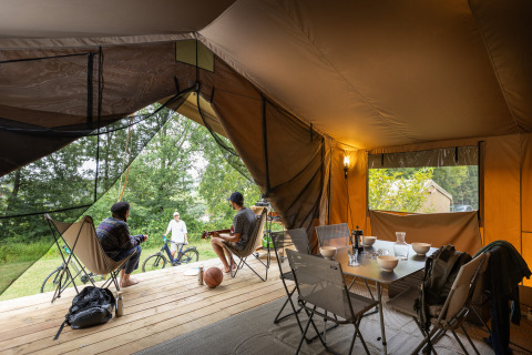 Vue intérieure d'une tente bungalow safari avec des personnes à Huttopia Chardons Bleus - Ile de Ré, France.