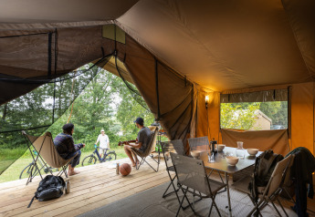 Inside view of a safari bungalow tent with people relaxing at Huttopia Chardons Bleus - Ile de Ré, France.