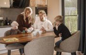 Gezin aan het ontbijten in holiday villa Amalia 6 in Hofparken Wiltershaar, Nederland, bij ochtendlicht.