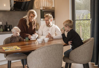 Family enjoys breakfast together at the dining table in Holiday villa Amalia 6 at Hofparken Wiltershaar, Netherlands.