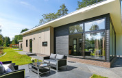 Moderne Lodge Grand Modern bij Holiday Park De Lochemse Berg in Nederland met terras en tuinzicht.