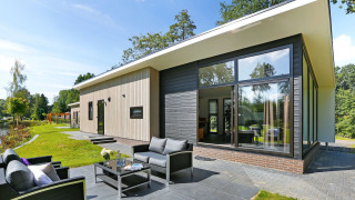 Moderne Lodge Grand Modern bij Holiday Park De Lochemse Berg in Nederland met terras en tuinzicht.