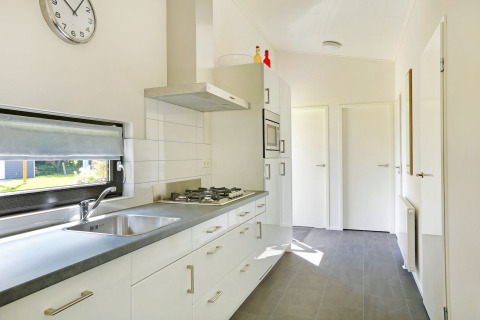 Moderne køkkenindretning i Lodge Grand Modern på Holiday Park De Lochemse Berg med hvide skabe og vindue.