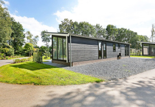 Modernes Lodge Grand im Holiday Park De Lochemse Berg, Niederlande, umgeben von Natur und viel Grün.