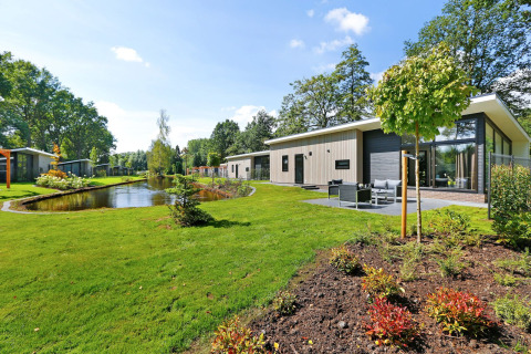 Lodge moderne au bord d’un étang dans le Holiday Park De Lochemse Berg, Pays-Bas, cadre verdoyant.