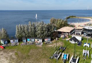Luftfoto af Tiny Wagon lodge ved Marina Parcs Almere, Holland, med hytter langs søbredden.