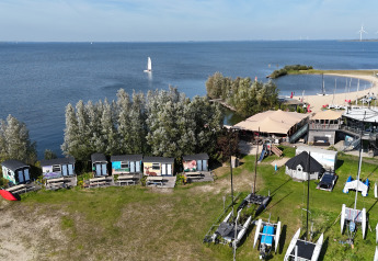 Vue aérienne du lodge Tiny Wagon à Marina Parcs Almere, Pays-Bas, avec cabanes au bord du lac.