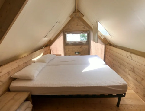 Interior view of a cozy bed in the Air Dreamer safari tent at Vacanze Glamping Boutique in Italy.