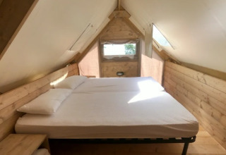 Interior view of a cozy bed in the Air Dreamer safari tent at Vacanze Glamping Boutique in Italy.