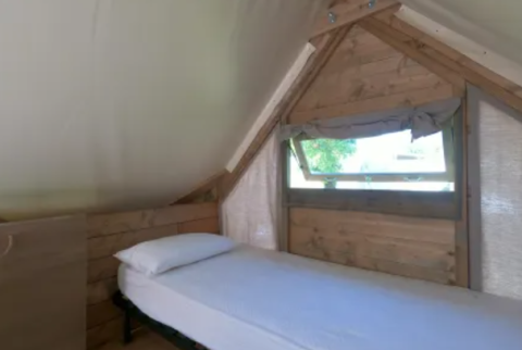 Single bed and window inside an Air Dreamer safari tent at Vacanze Glamping Boutique in Italy.