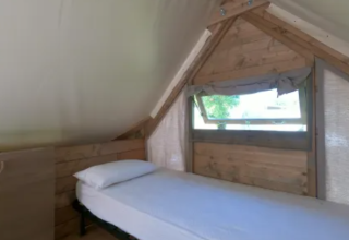 Single bed and window inside an Air Dreamer safari tent at Vacanze Glamping Boutique in Italy.