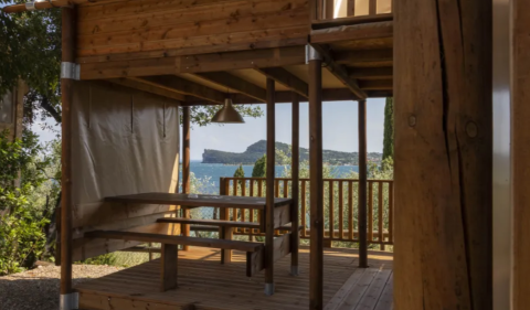 View from the Air Dreamer safari tent at Vacanze Glamping Boutique in Italy, showing a wooden terrace and sea.