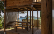 View from the Air Dreamer safari tent at Vacanze Glamping Boutique in Italy, showing a wooden terrace and sea.