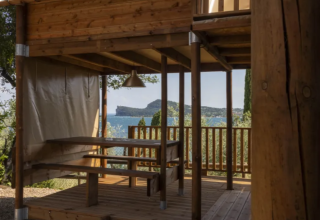 View from the Air Dreamer safari tent at Vacanze Glamping Boutique in Italy, showing a wooden terrace and sea.