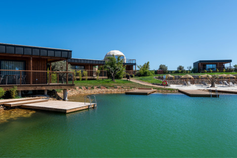 Zicht op Dome House Duplex Do Lago in Wecamp Reserva Alecrim, Portugal, met meer, houten lodges en zonnedekken