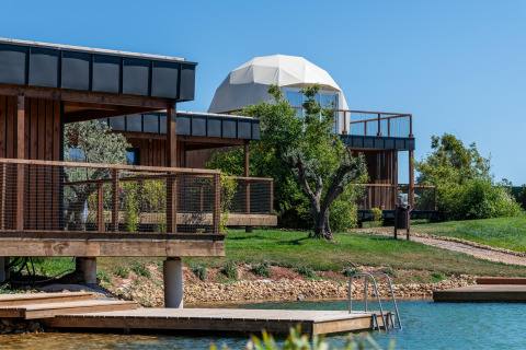 Uitzicht op Dome House Duplex Do Lago bij Wecamp Reserva Alecrim in Portugal, met houten lodges en vijver.