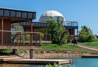 Uitzicht op Dome House Duplex Do Lago bij Wecamp Reserva Alecrim in Portugal, met houten lodges en vijver.