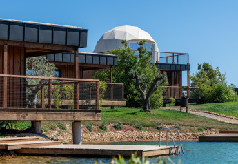 Vue sur le Dome House Duplex Do Lago à Wecamp Reserva Alecrim au Portugal, avec lodges en bois et lac.