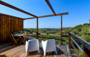 Terraza de madera del Bungalow Compact Wood en Wecamp Reserva Alecrim, Portugal, con vistas a la naturaleza.