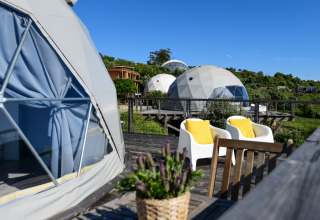 Buitenaanzicht van de Couple Domes bij Wecamp Reserva Alecrim in Portugal met zitplaats en groen landschap.