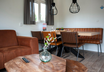 Wohnbereich in der Veluwelodge XL im De Boshoek Park, mit braunen Möbeln, Holztisch und Essbereich.