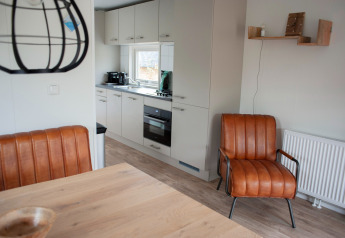 Moderne Küche und Wohnbereich in der Veluwelodge XL im Recreation park De Boshoek, Niederlande, mit Ledersesseln.