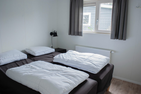 Slaapkamer in Veluwelodge XL, Recreatiepark De Boshoek, Nederland met twee bedden en raam.