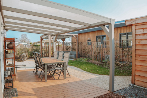 Overdekt terras aan Veluwelodge XL in Recreation park De Boshoek met tuintafelset en relaxstoelen.