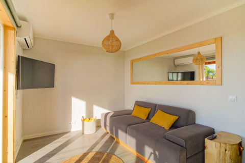 Lichte woonkamer in Dome House bij Wecamp Reserva Alecrim, Portugal, met grijze sofa en spiegels.