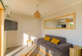 Lichte woonkamer in Dome House bij Wecamp Reserva Alecrim, Portugal, met grijze sofa en spiegels.
