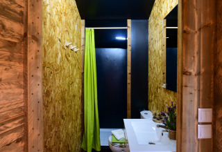 Badkamer in de Lodge Family safaritent bij Wecamp Reserva Alecrim, Portugal, met groen douchegordijn.