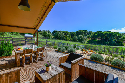 Buitenterras met houten meubels en uitzicht op groene heuvels bij Lodge Family, Wecamp Reserva Alecrim, Portugal.