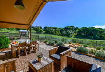 Terrasse mit Holzmöbeln und Blick auf grüne Hügel am Safari-Zelt Lodge Family, Wecamp Reserva Alecrim, Portugal.