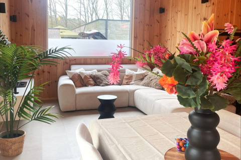 Modern lodge living room at Lysdann in Belgium with a cozy corner sofa and vibrant floral arrangements.