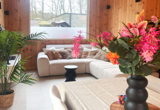 Modern lodge living room at Lysdann in Belgium with a cozy corner sofa and vibrant floral arrangements.