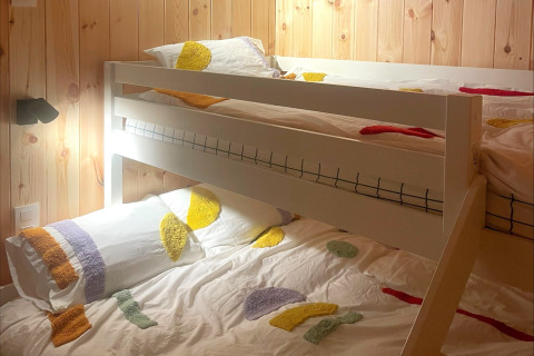 A cozy room with bunk beds and colorful bedding at Lysdann lodge in Belgium, featuring wood paneled walls.