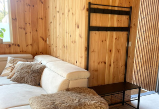 Modern living room at Lysdann lodge in Belgium, featuring wood panel walls and beige sofa.