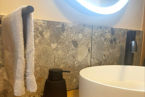 Bathroom scene at Lysdann lodge in Belgium showing a round sink, towel, black soap dispenser and faucet.