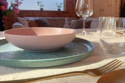 Table setting at Lysdann lodge in Belgium with pastel bowl, glasses, and gold cutlery in natural sunlight.