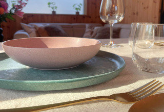 Table setting at Lysdann lodge in Belgium with pastel bowl, glasses, and gold cutlery in natural sunlight.