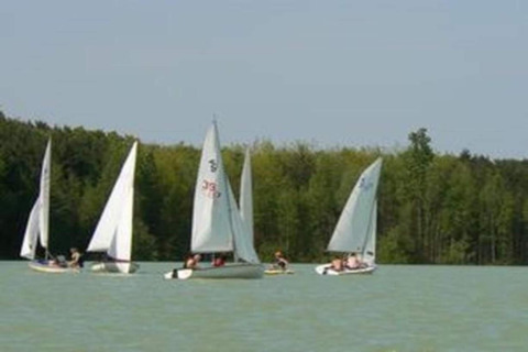 Sailboats on the lake at Lysdann lodge in Belgium, surrounded by trees and under a clear sky.