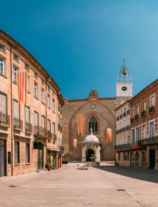Vista panorámica de una pintoresca plaza en Espira de Conflent, Occitanie, Francia, con edificios históricos y una iglesia.