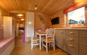 Acogedor interior con paneles de madera del mobil home Manureva en Bélgica, mesa comedor y literas.