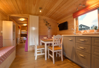 Acogedor interior con paneles de madera del mobil home Manureva en Bélgica, mesa comedor y literas.